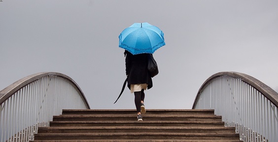 Person walking outside up steps with an umbrella